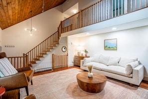 A spacious living area with a staircase, a sofa, a coffee table, and a painting on the wall.