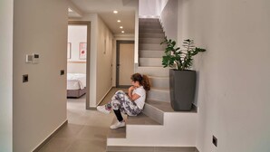 A staircase with a potted plant, a person sitting on the steps, and a bedroom visible in the background.