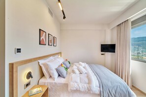 Ein Hotelzimmer mit Bett, Fernseher, Fenster mit Blick und Wandbildern.