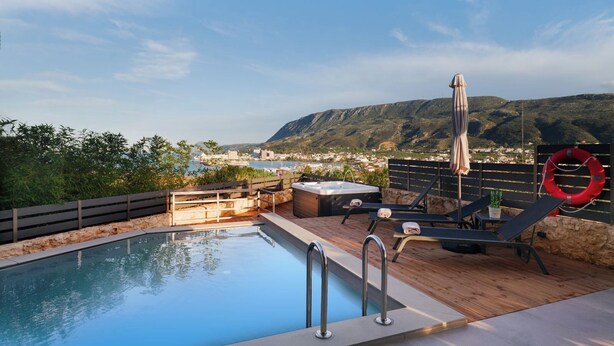 A rooftop pool area with a hot tub, lounge chairs, and a lifebuoy.