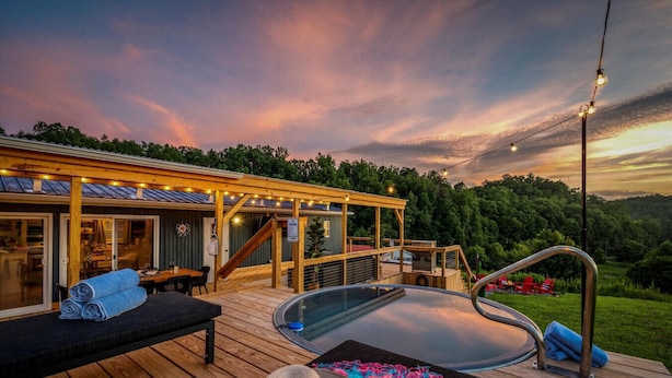 A wooden deck with a hot tub, lounge chairs, and a covered seating area.