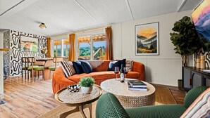 A modern living room with a sofa, coffee table, and a dining area with chairs and a table.