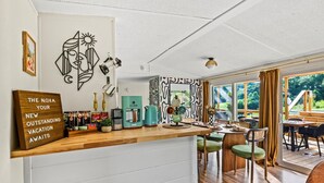 A modern kitchen with a wooden countertop, a coffee machine, and a sign that reads "THE NOVA, YOUR NEW OUTSTANDING VACATION AWAITS".