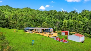 A house with a deck, a red shed, and a green lawn.