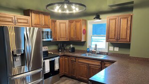 A modern kitchen with stainless steel appliances, wooden cabinets, a granite countertop, and a pendant light. - 2 houses, huge yard, dog-friendly, close to ORV trails and lakes (St. Helen)