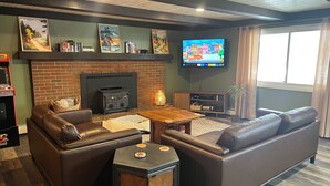A cozy living room with leather sofas, a fireplace, a flat-screen TV, and a bookshelf. - 2 houses, huge yard, dog-friendly, close to ORV trails and lakes (St. Helen)