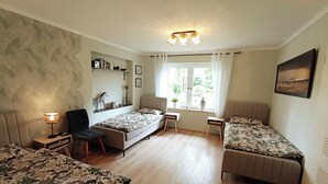 A bedroom with two single beds, a desk, a chair, a lamp, and a window with curtains.