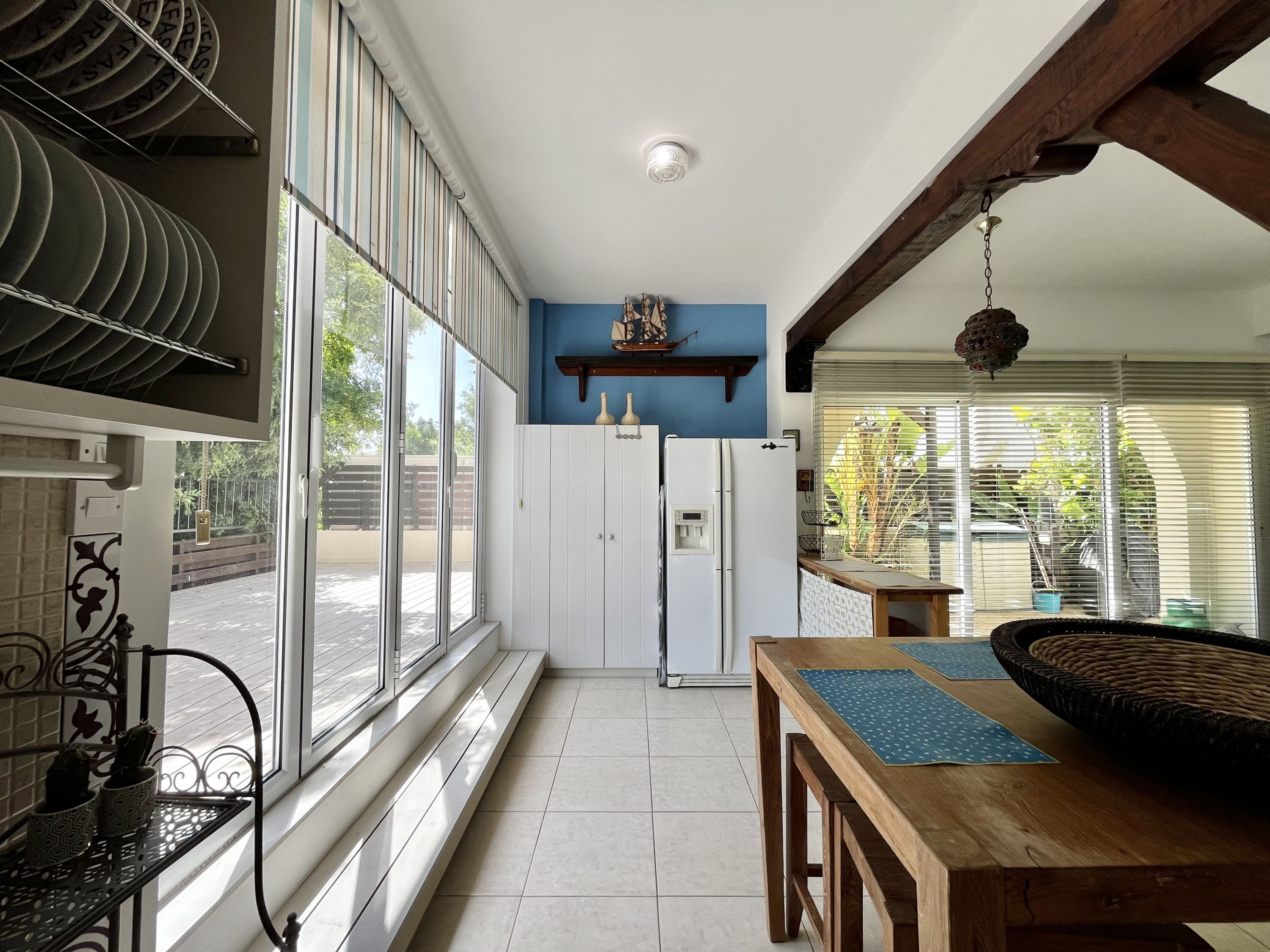 A kitchen with a large window, a refrigerator, and a dining table with a placemat.