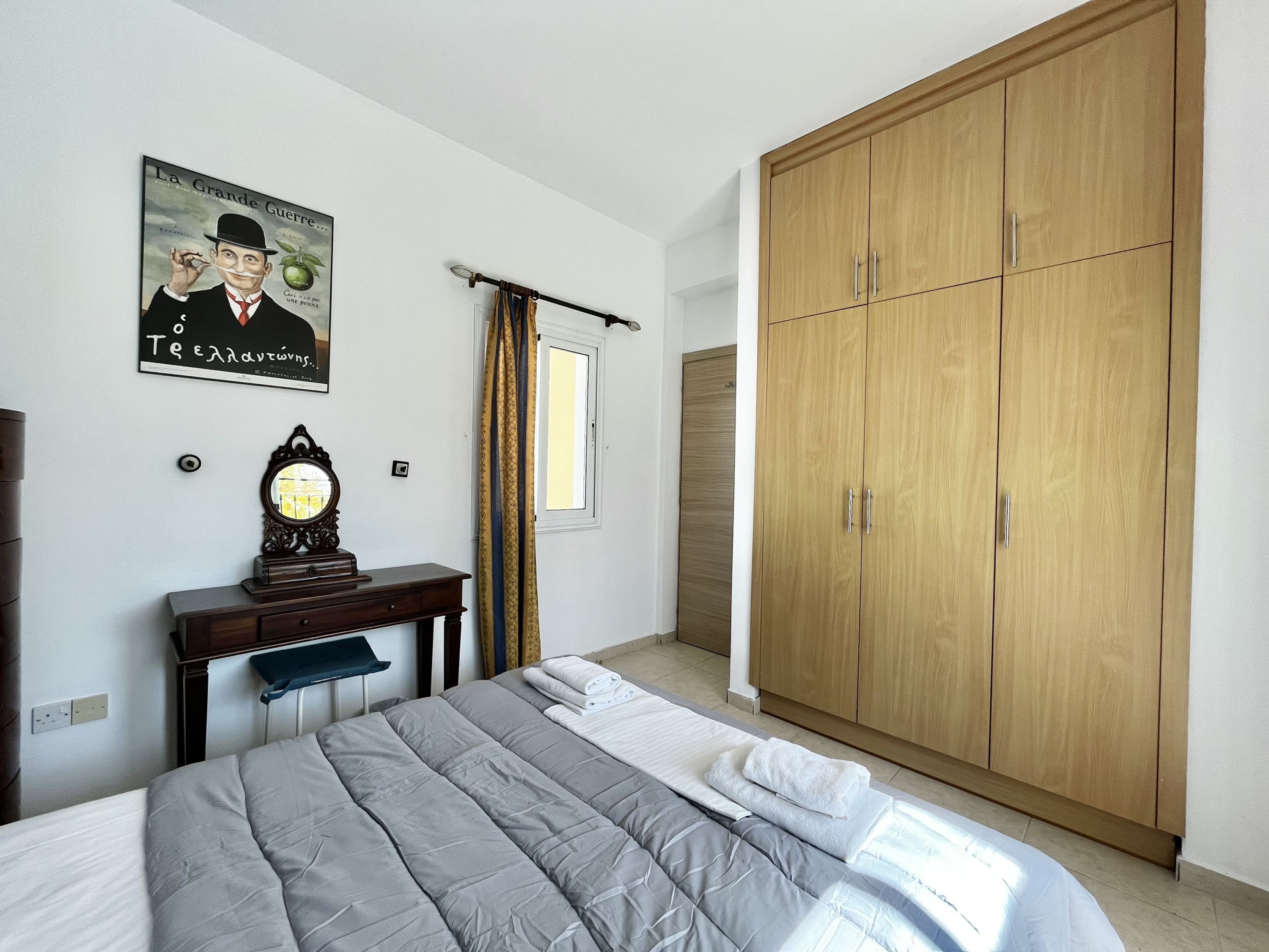 A bedroom with a bed, a wardrobe, a mirror, and a poster on the wall.