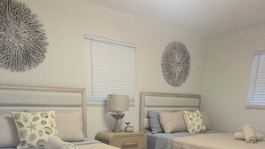 Ein Schlafzimmer mit zwei Betten, einem Nachttisch mit Lampe und einer Wanddekoration.