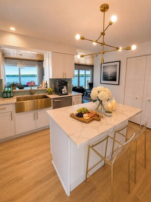 A modern kitchen with a large island, a coffee machine, and a view of the outdoors. - Boutique Lakefront Cottage, Hot Tub, Sauna (Henderson)