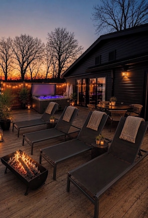 A deck with lounge chairs, a fire feature, and a hot tub. - Boutique Lakefront Cottage, Hot Tub, Sauna (Henderson)