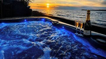 Boblebad med udsigt til solnedgang, to glas og en champagneflaske.