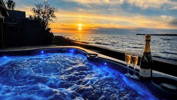 A hot tub with a sunset view, two glasses, and a bottle of champagne.