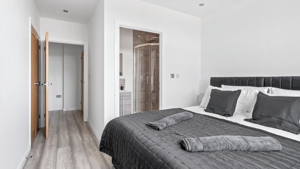Un dormitorio moderno con una cama grande, un vestidor y una ducha de vidrio.