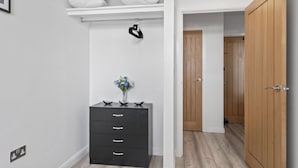 Un dormitorio con cama, cómoda, espejo y puerta que da a otra habitación.