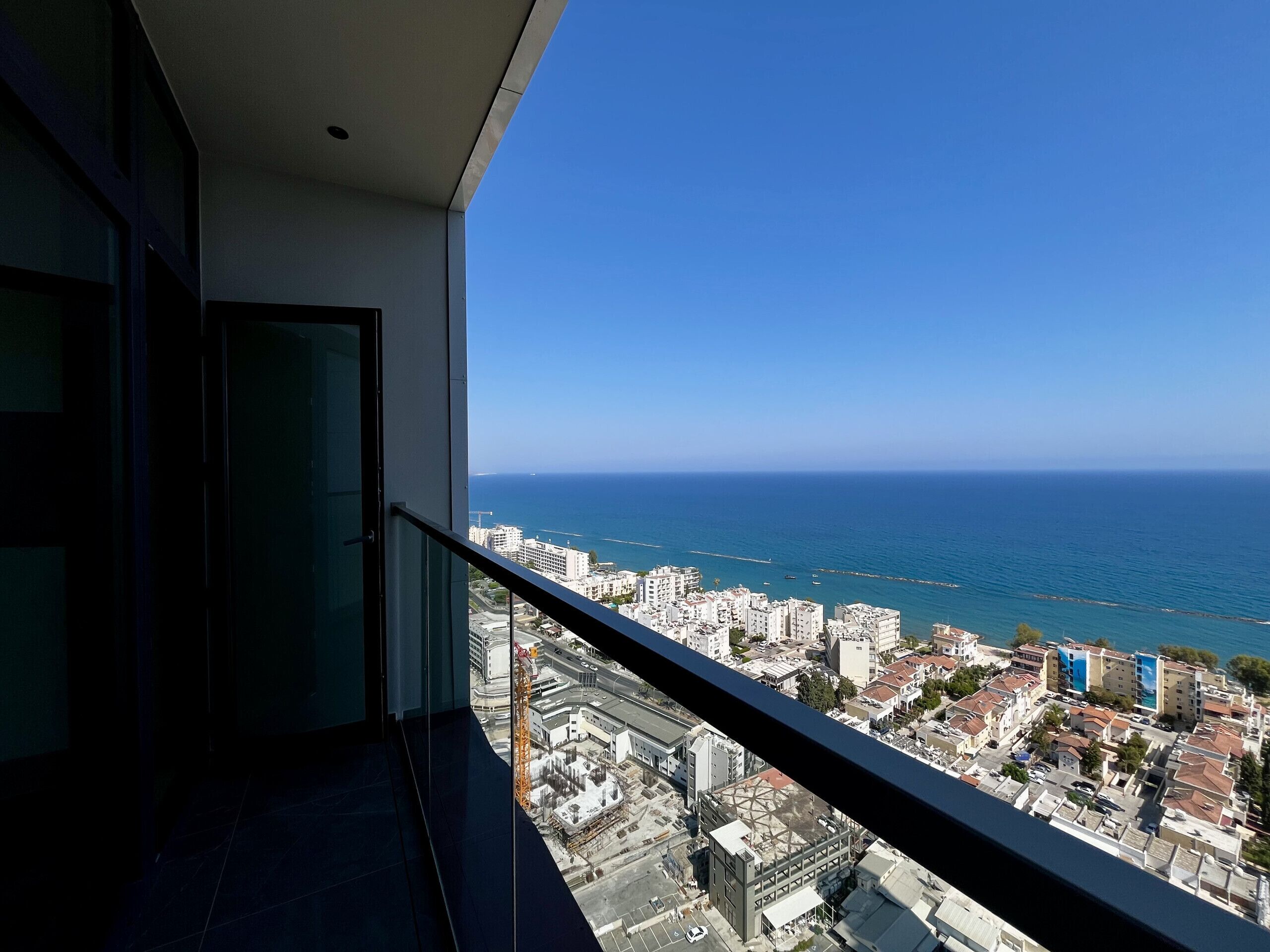 A balcony with a view of the sea and cityscape.