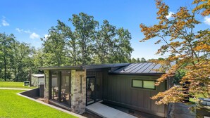 Ein modernes Haus mit Natursteinfassade, einem Glastür-Eingang und einer kleinen Veranda.