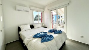 Un dormitorio moderno con una cama grande, ropa de cama blanca y vistas al balcón exterior.