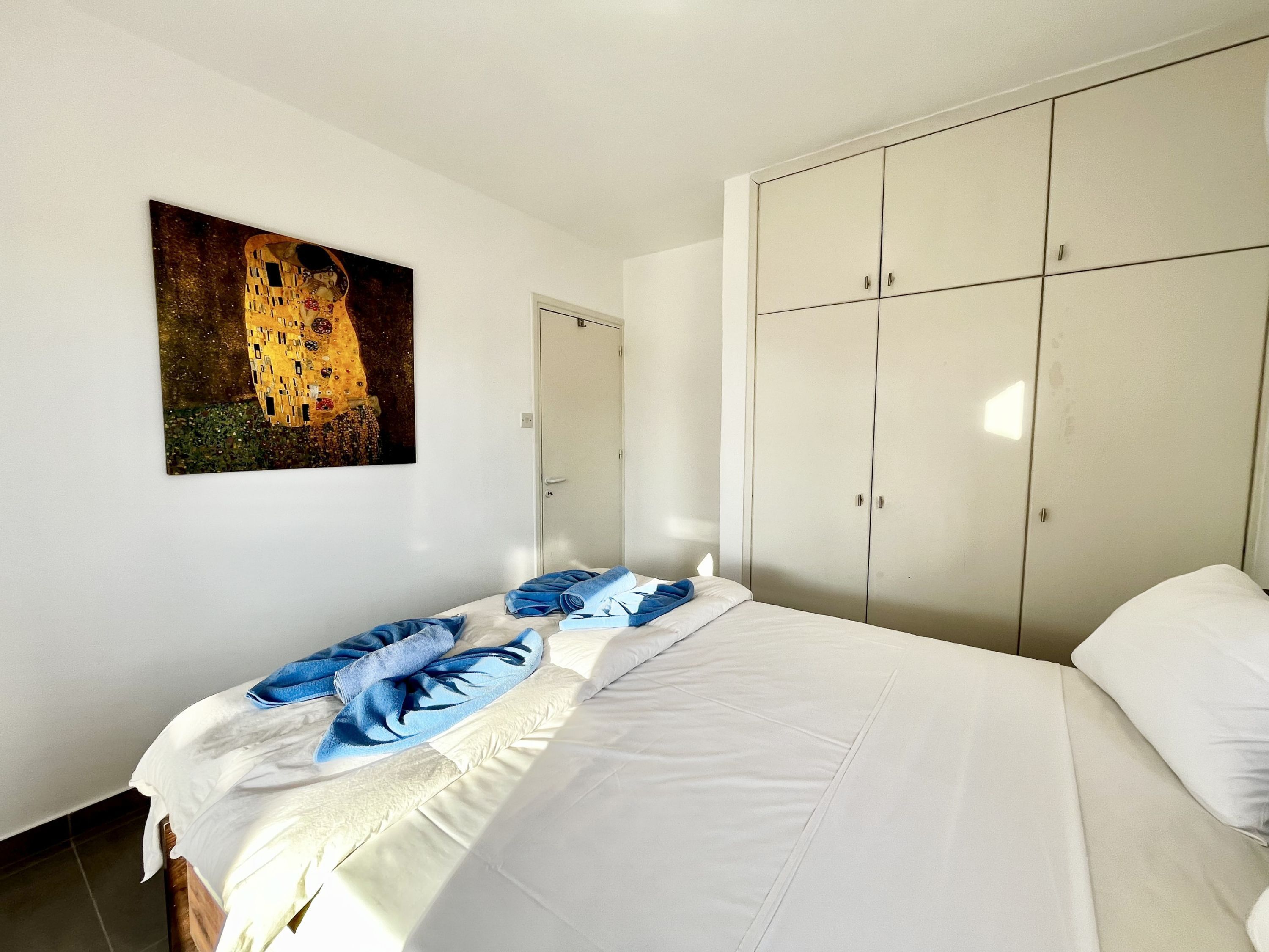 Un dormitorio con cama, armario y un cuadro en la pared.