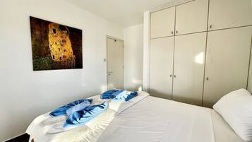 Un dormitorio con cama, armario y un cuadro en la pared.