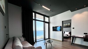Ein modernes Hotelzimmer mit einem großen Fenster, einem Sofa, einem kleinen runden Tisch und einem Bett.