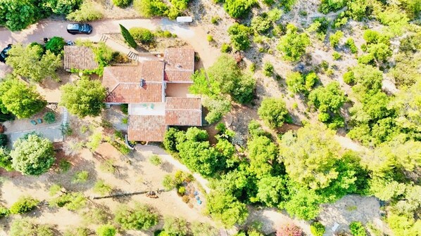 Vue aérienne d’une propriété avec un bâtiment central entouré d’arbres et une allée pavée.