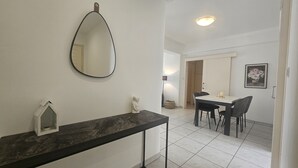 A modern bathroom with a marble vanity, a round mirror, and a small sculpture.