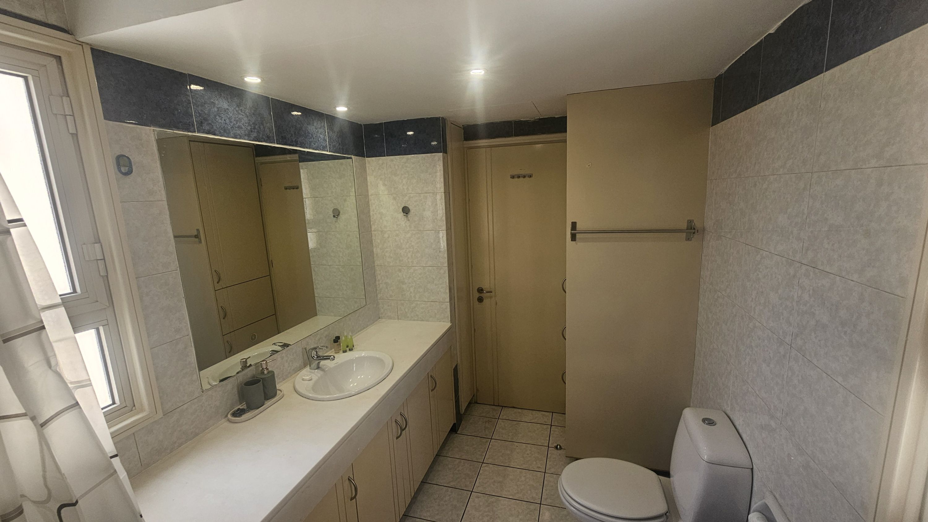 Une salle de bain équipée d’un lavabo, d’un miroir, de toilettes et d’un espace douche.