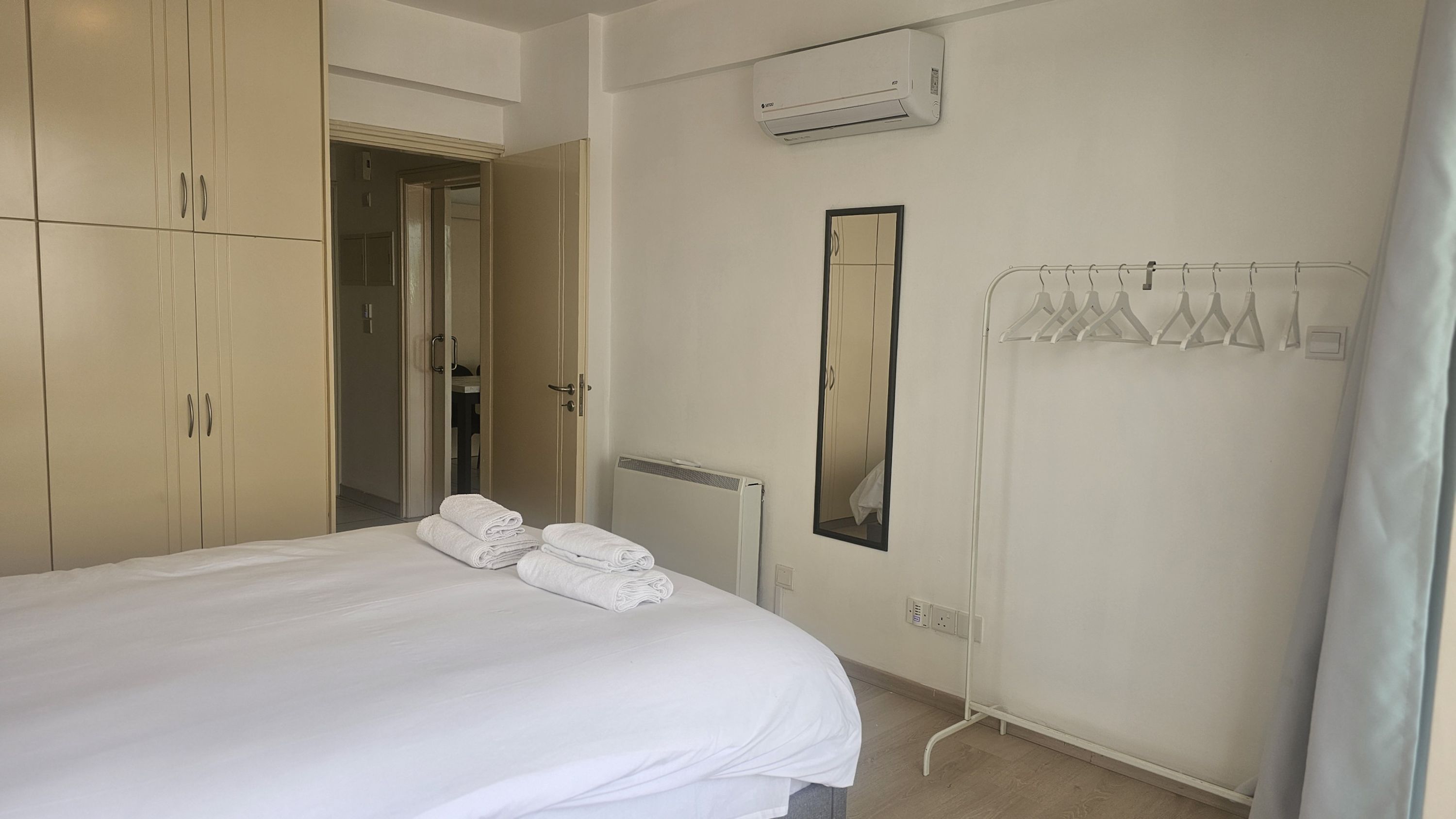 Una habitación de hotel con cama, armario, radiador y espejo.