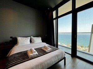 Een hotelkamer met een groot bed, een nachtkastje en uitzicht op zee.