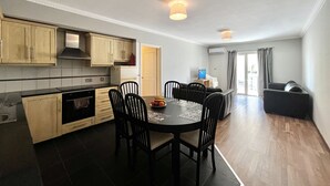 Eine kleine Küche mit Holzschränken, einem Esstisch mit Stühlen und einer Sitzecke mit einer Couch.