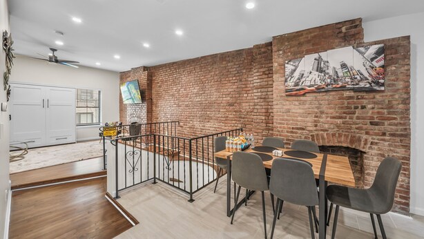 A dining area with a brick wall, a fireplace, and a cityscape painting.