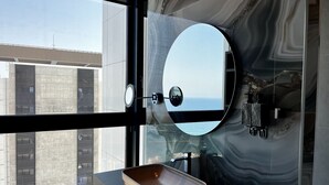 A modern bathroom with a large window, a round mirror, and a marble backsplash. - 128 LIM - 2005 Stay Only Tower Suite (Limassol)
