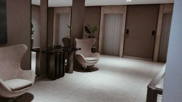 A lobby with two armchairs and a small table, a tiled floor, and a door in the background. - Mina Hotel  (Riyadh)