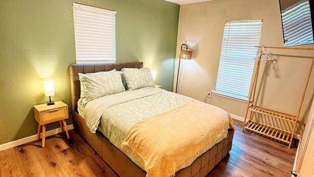 Un dormitorio con cama, mesitas de noche, lámpara y espejo.