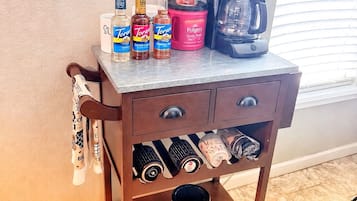 A kitchen cart with storage drawers, a coffee maker, and various condiments.
