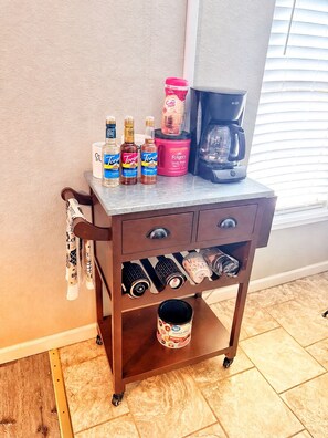 Un carrito de cocina con cajones de almacenamiento, una cafetera y diferentes condimentos.