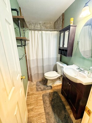 A bathroom with a toilet, sink, and shower curtain. - Modern Downtown 1-Bedroom • Pet-Friendly Stay with Yard (Fort Smith)