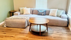 Una sala de estar con un sofá modular, una mesa de centro redonda y piso de madera.