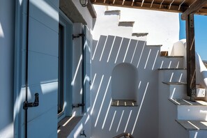 A white building with a blue door, a wooden pergola, and a clear blue sky. - Akti Giannaki (Tinos)
