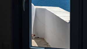 A view through a door of a balcony with a white wall and a clear blue sky. - Akti Giannaki (Tinos)