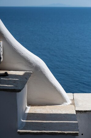 A white staircase leading to a balcony overlooking a body of water. - Akti Giannaki (Tinos)