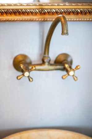 A bathroom with a brass faucet and a wall-mounted mirror. - Akti Giannaki (Tinos)