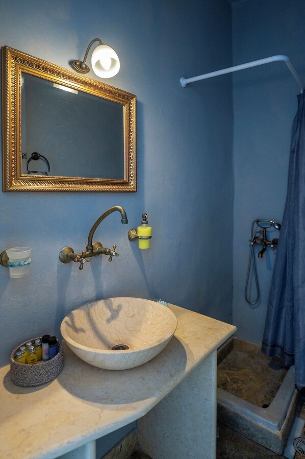 A bathroom with a sink, mirror, shower, and towel rack. - Akti Giannaki (Tinos)