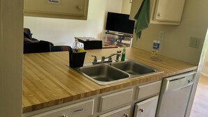 A kitchen with two sinks, a microwave, and cabinets labeled 'MUGS,' 'GLASSES,' 'UTENSILS,' and 'FIRE EXTINGUISHER.'