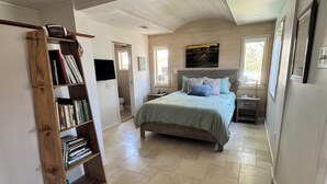 Un dormitorio espacioso con una cama grande, una estantería de madera y un ventilador de techo.
