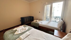 A hotel room with two beds, a crib, and a large window with a view of the outside. - 115 AN - Stay Napa Oniro Apartment (Ayia Napa)