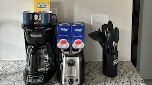 Una cocina con cafetera, tostadora y cajas de azúcar sobre el mostrador.
