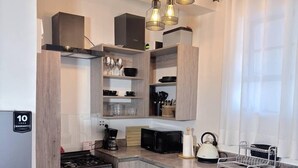 Een moderne keuken met een gasfornuis, magnetron en houten kastjes. Op de vloer ligt een zwart-wit tapijt.